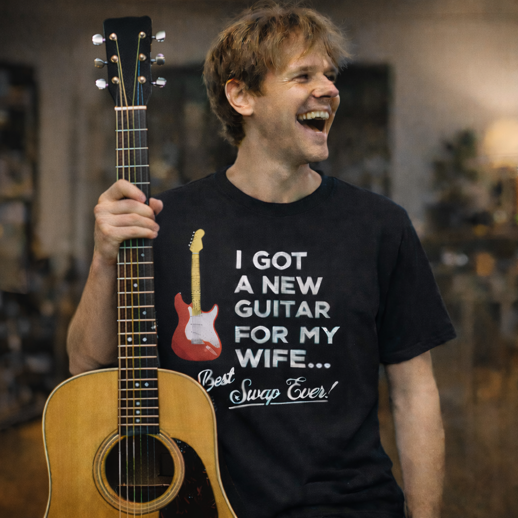 Laughing man wearing a black t-shirt that says "I Got A New Guitar For My Wife."